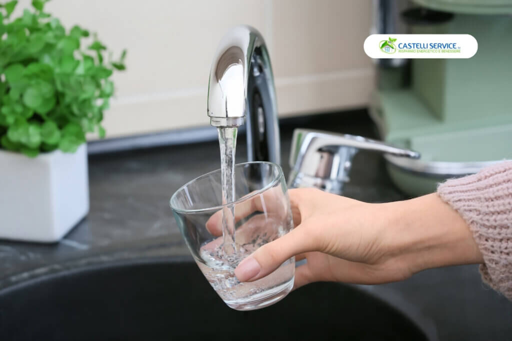 la mano di una ragazza che sta riempiendo un bicchiere con acqua del rubinetto grazie al depuratore